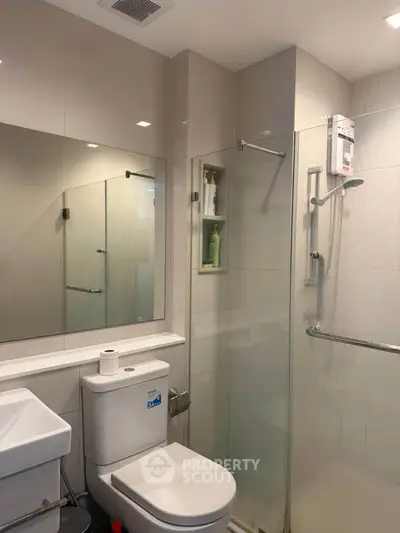 Modern bathroom with glass shower and sleek fixtures in contemporary apartment.