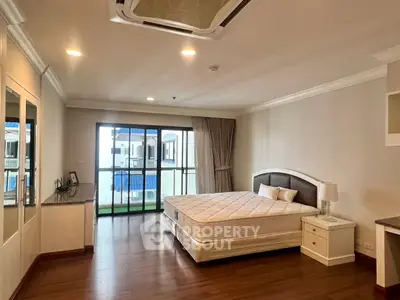 Spacious bedroom with large windows and balcony access in modern apartment.