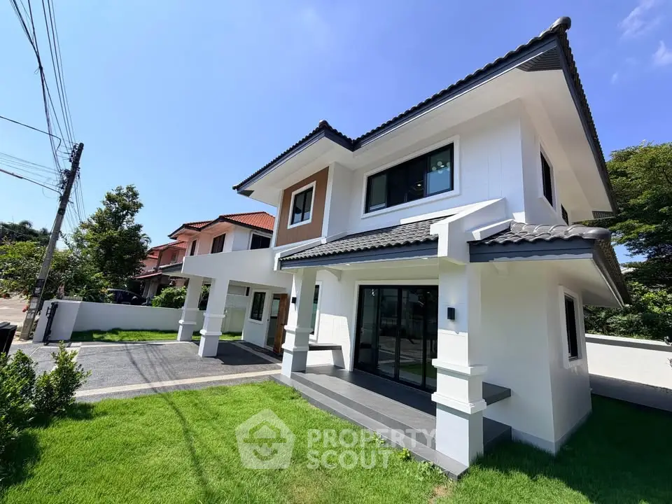 Modern two-story house with sleek design and lush green lawn under a clear blue sky.