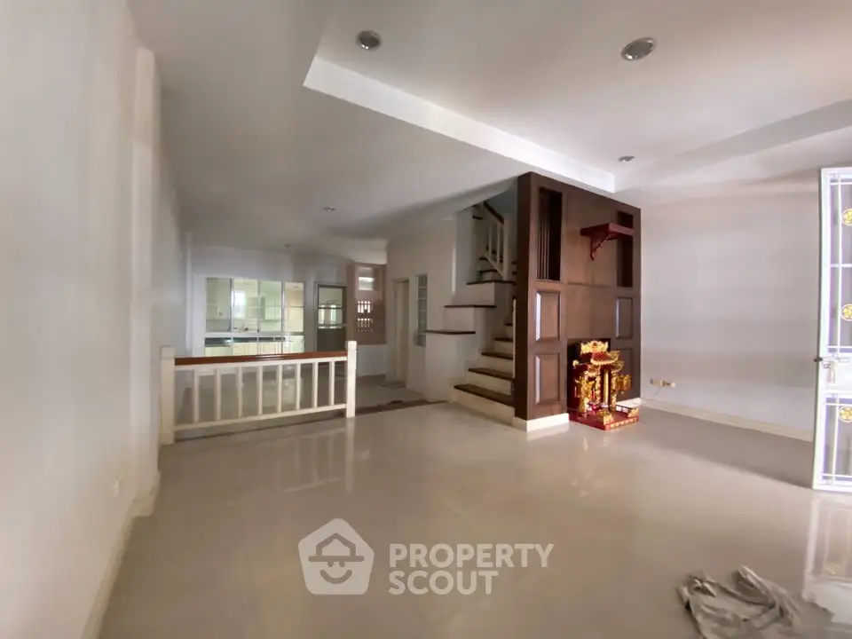 Spacious open-plan living area with modern staircase and ample natural light.