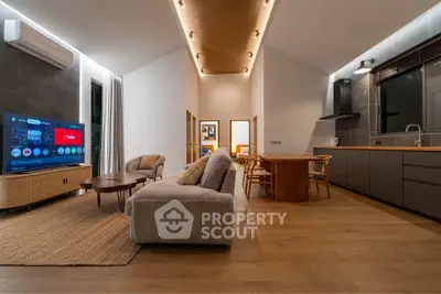 Modern open-plan living room with stylish furniture and integrated kitchen area, featuring warm lighting and sleek design.