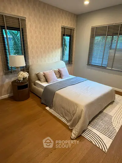 Cozy bedroom with stylish decor and natural light from multiple windows.