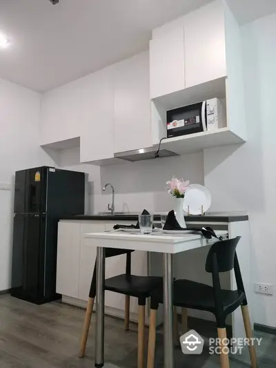 Modern compact kitchen with dining area, featuring sleek cabinetry and appliances.