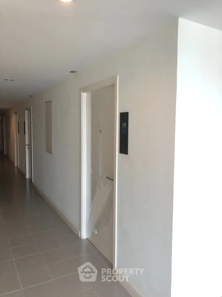 Modern apartment corridor with sleek design and room number signage, showcasing contemporary living spaces.