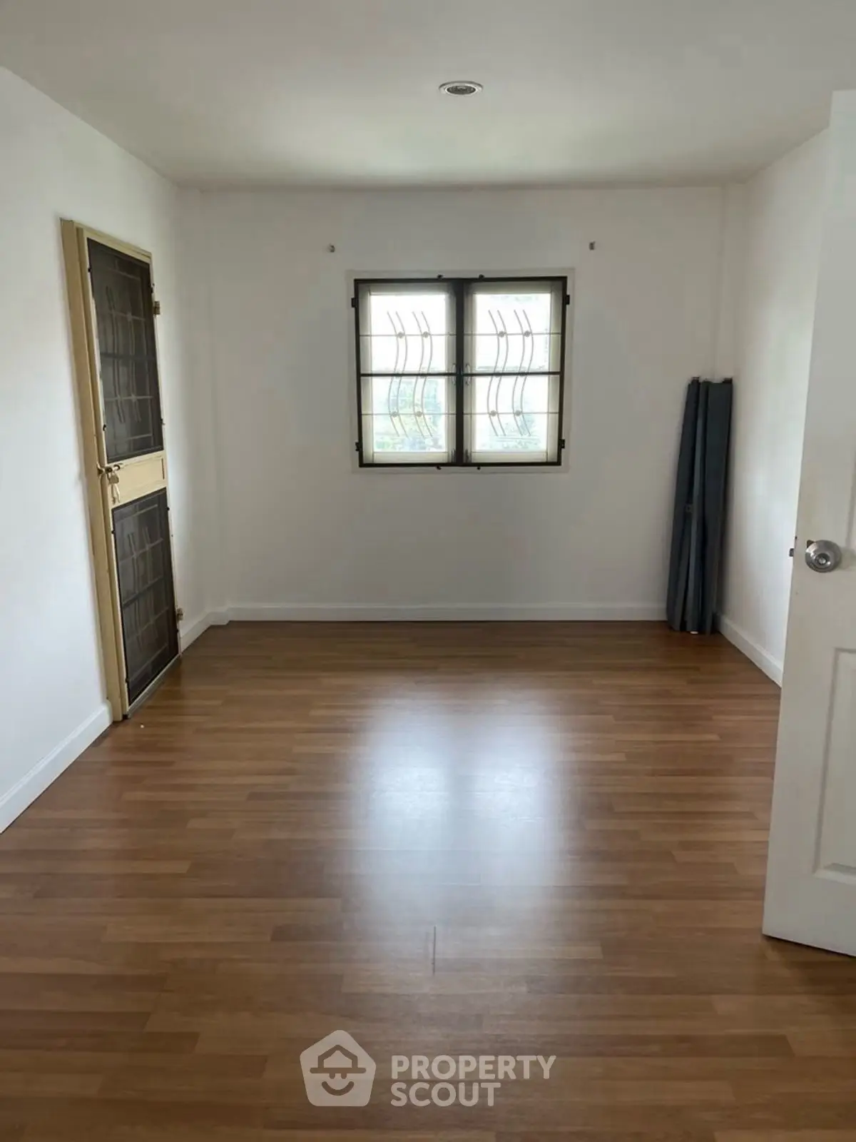 Spacious empty room with wooden flooring and natural light, ideal for customization.