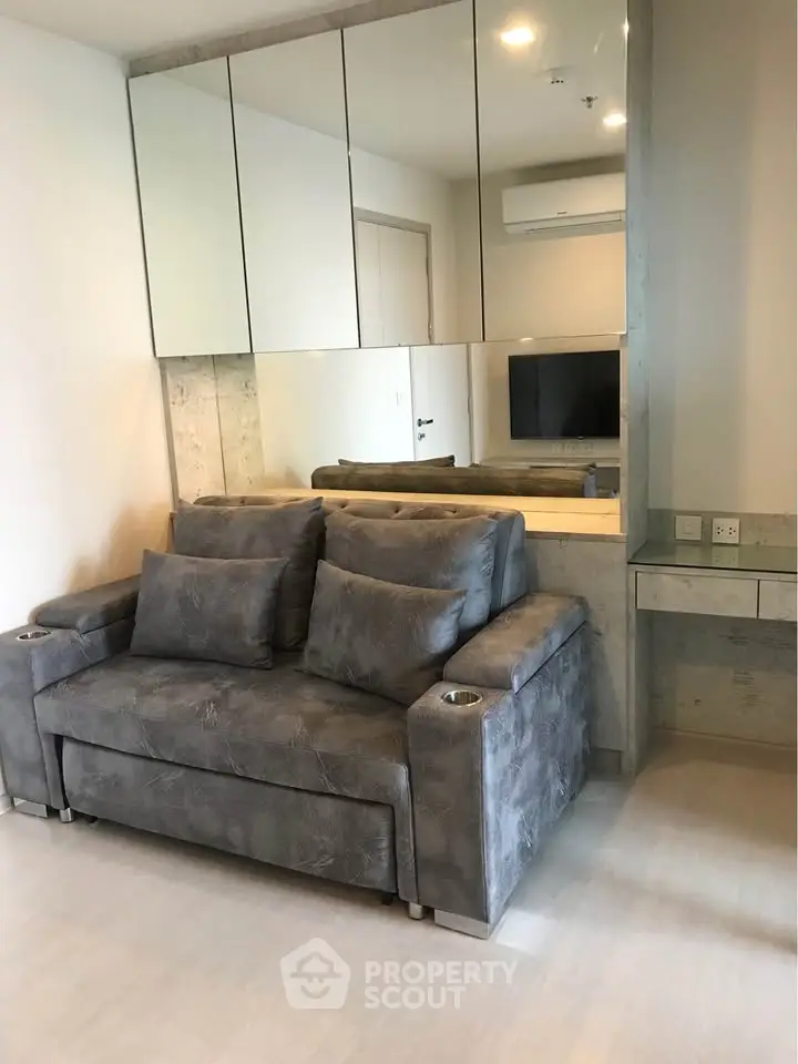 Modern living room with stylish gray sofa and mirrored wall accents