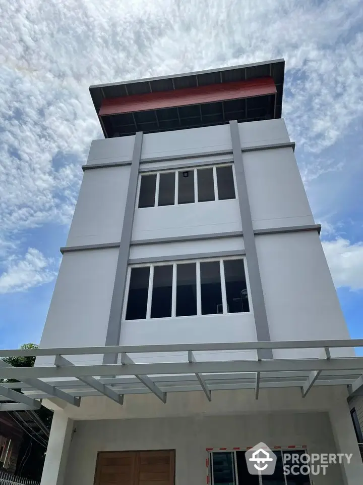 Modern multi-story building with sleek design and large windows under a clear blue sky.