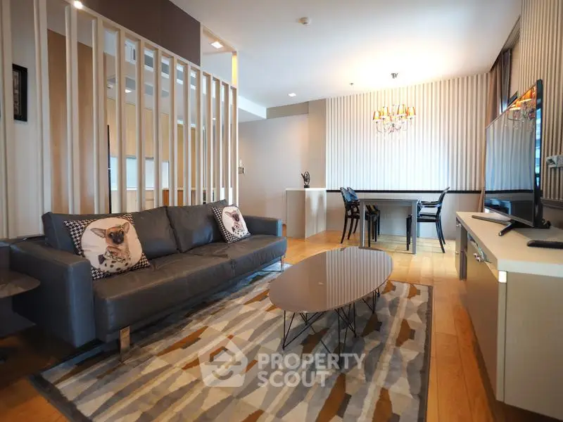 Modern living room with stylish decor and open dining area, featuring a sleek sofa and contemporary lighting.
