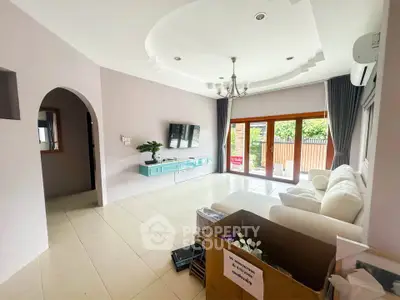 Spacious living room with modern decor and large windows opening to a garden view.