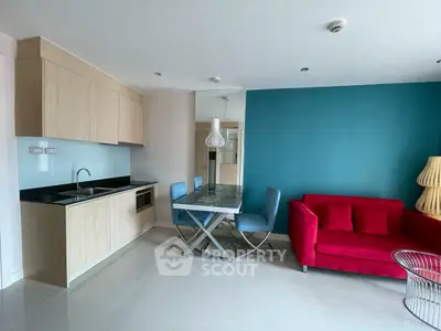 Modern open-plan living room with vibrant red sofa and sleek kitchen area.