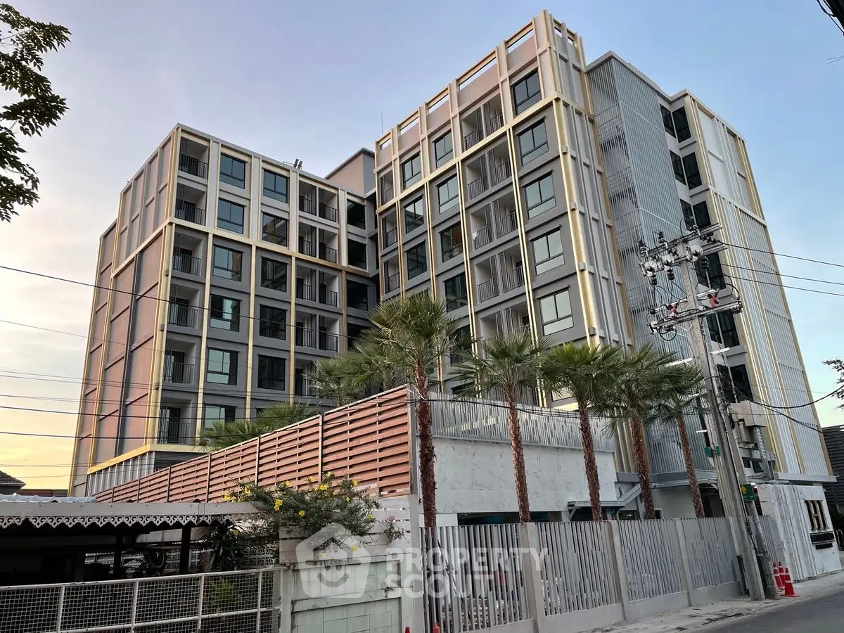 Modern multi-story residential building with contemporary design and palm trees in the foreground.