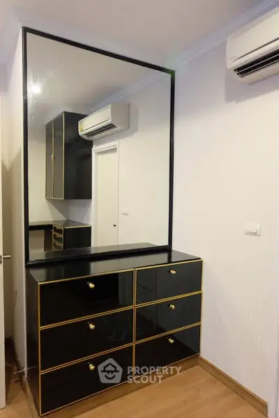 Modern bedroom with sleek black dresser and large mirror, featuring air conditioning for comfort.