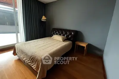 Cozy bedroom with modern decor and natural light from large window.