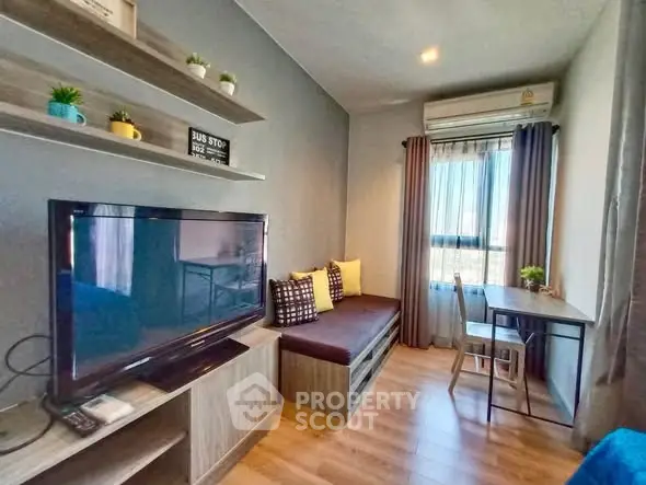 Modern living room with TV, cozy seating, and natural light from large window.