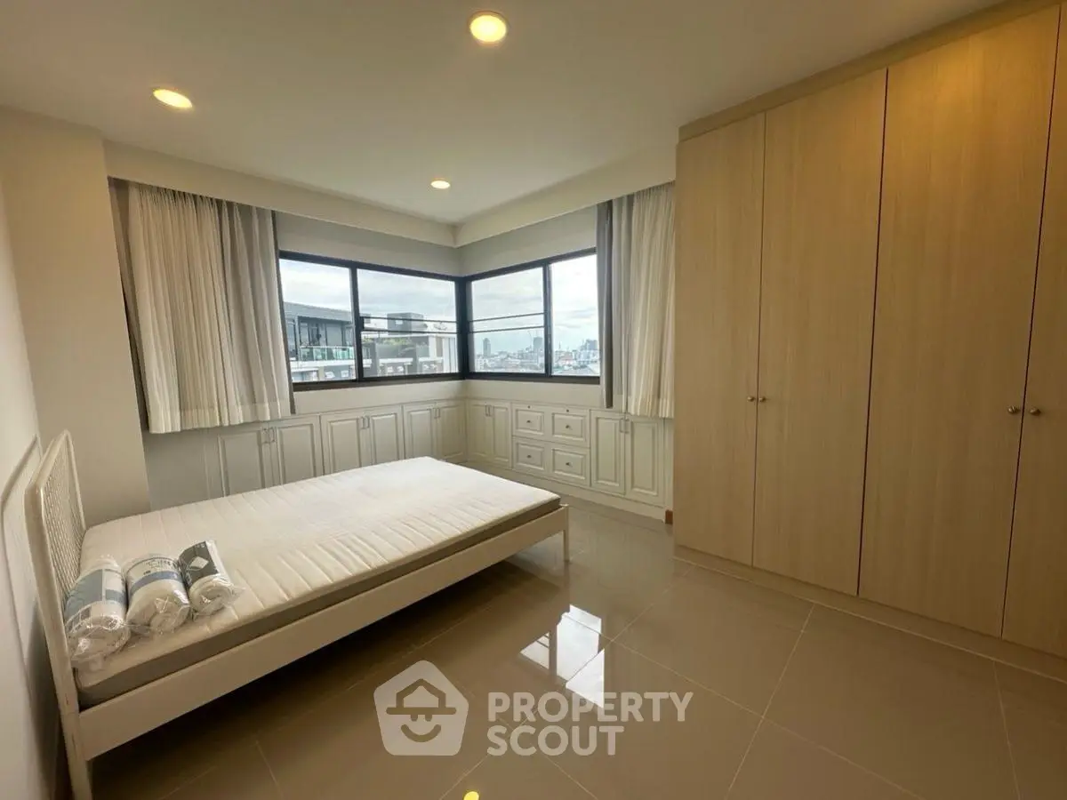 Spacious bedroom with large windows and built-in wardrobe offering city views.