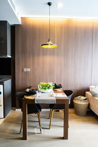 Modern dining area with stylish lighting and wooden accents in a cozy apartment.
