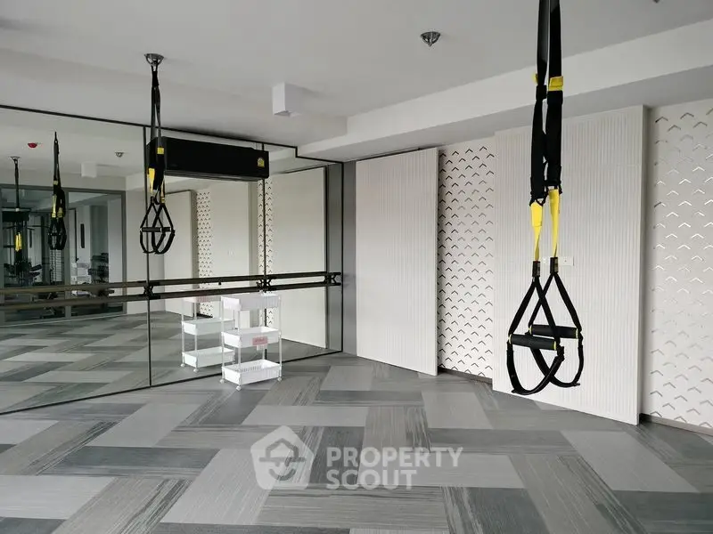 Modern gym with TRX equipment and mirrored walls in a stylish fitness center.