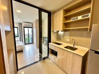 Modern apartment kitchen with open layout leading to a cozy bedroom and balcony view.