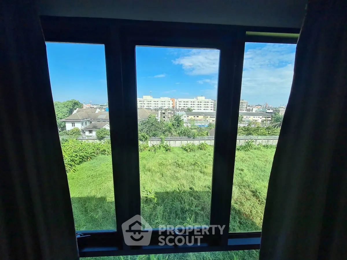 Stunning cityscape view from a large window, showcasing lush greenery and urban skyline.