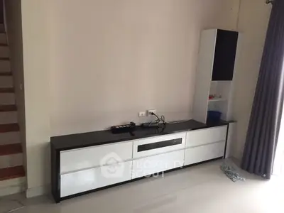 Modern minimalist living room with sleek white furniture and staircase