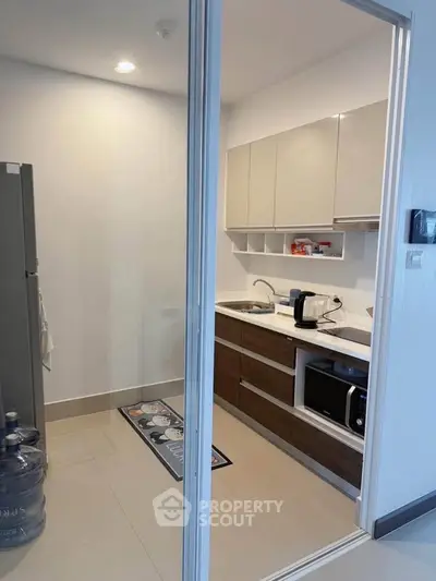 Modern compact kitchen with sleek cabinets and appliances in a cozy apartment.