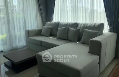 Spacious living room with modern gray sectional sofa and large windows for natural light.
