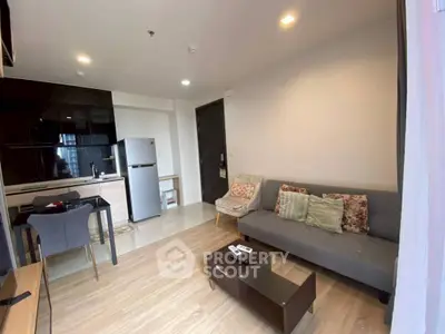 Modern living room with sleek kitchen and cozy seating area in stylish apartment.