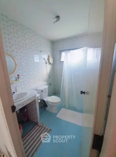 Cozy bathroom with shower curtain and blue tile flooring in a bright home.