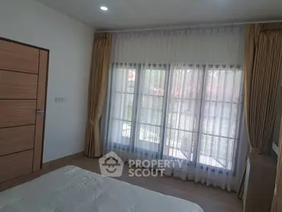 Spacious bedroom with large windows and elegant curtains, offering ample natural light and a serene atmosphere.