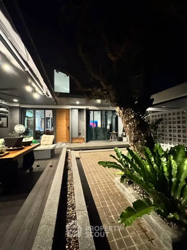 Modern exterior night view with stylish lighting and lush greenery, showcasing contemporary architectural design.