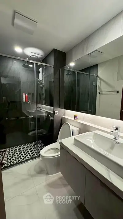 Modern bathroom with sleek design, featuring a glass shower enclosure and contemporary fixtures.