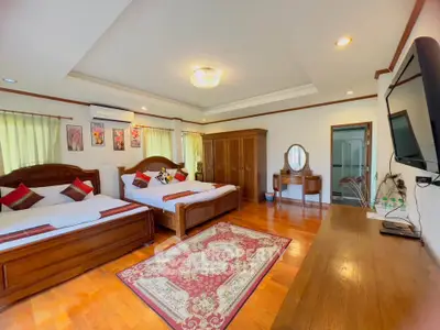Spacious bedroom with wooden flooring and elegant decor, featuring two beds and a TV.
