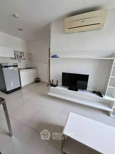Modern minimalist living room with air conditioning and compact kitchen area.