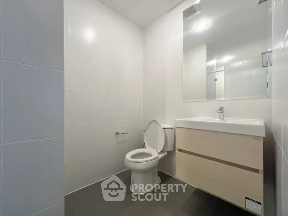 Modern bathroom with sleek fixtures and minimalist design, featuring a large mirror and contemporary vanity.