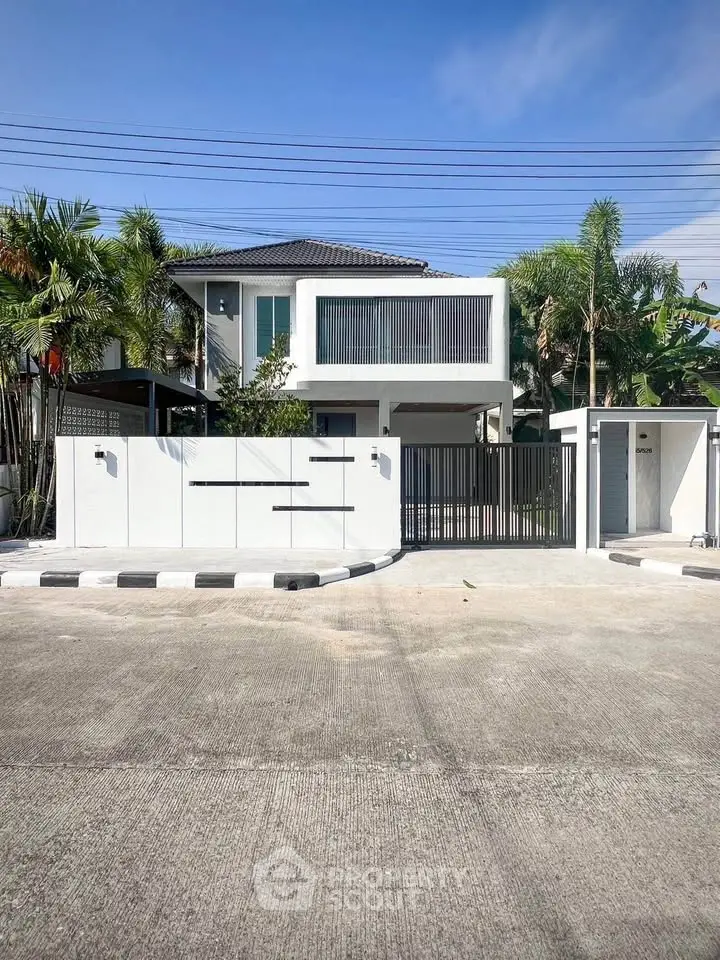 Modern two-story house with sleek design and gated entrance in tropical setting.