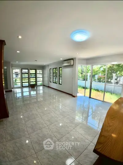 Spacious living room with large windows and garden view, perfect for natural light lovers.