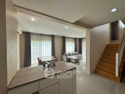 Spacious living room with modern decor and natural light, featuring a cozy sofa and elegant dining area.