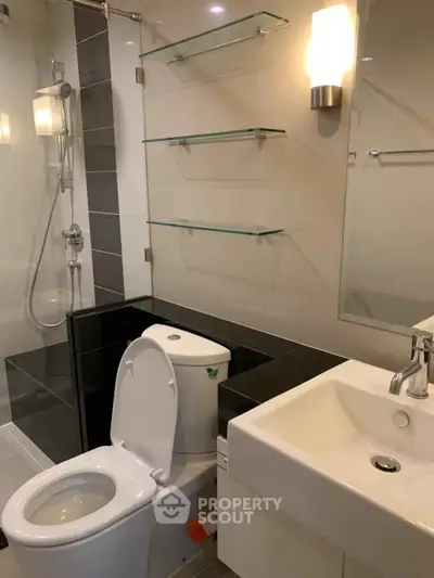 Modern bathroom with sleek fixtures and glass shelving in a contemporary apartment.