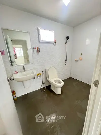 Spacious bathroom with modern fixtures and tiled walls, featuring a shower and toilet.
