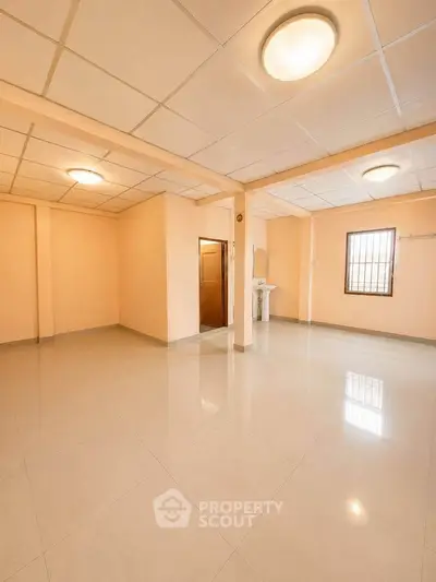 Spacious empty room with tiled flooring and ceiling lights, ideal for customization.