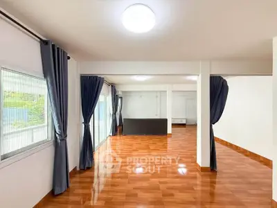 Spacious open-plan living area with polished wooden floors and large windows.