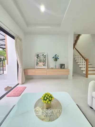 Modern living room with elegant decor and natural light, featuring a stylish staircase and cozy ambiance.