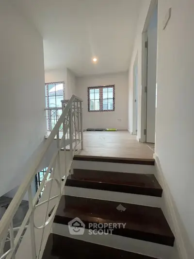 Bright and airy staircase leading to a modern upper floor landing with large windows.