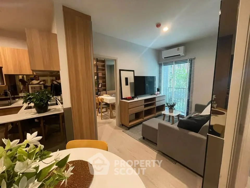Modern living room with stylish decor and open kitchen layout, featuring natural light and cozy ambiance.