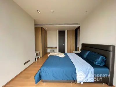 Spacious bedroom with large bed, modern built-in wardrobe, and hardwood flooring in a contemporary apartment.