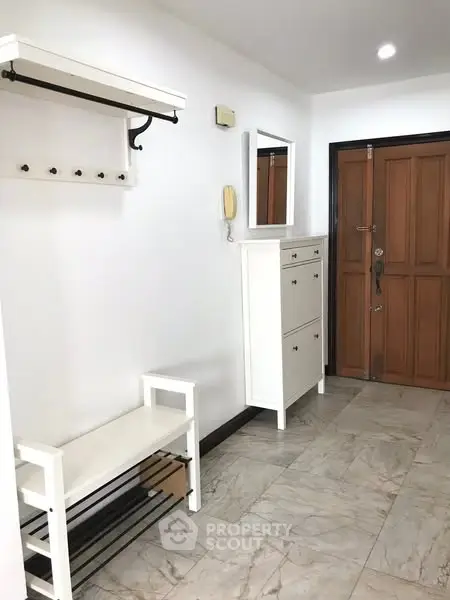 Spacious entryway with modern white furniture and wooden door