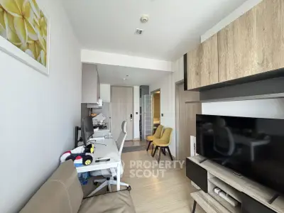 Modern living room with sleek furniture and large TV in a cozy apartment setting.