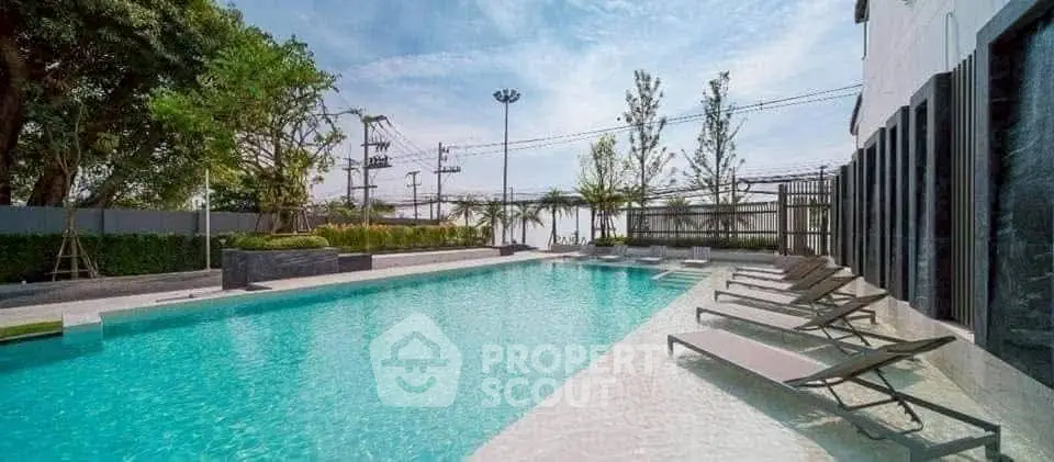 Luxurious outdoor pool area with sun loungers and lush greenery, perfect for relaxation.