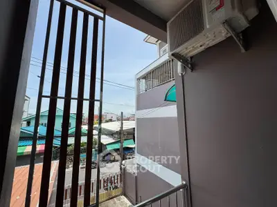 Charming balcony view with air conditioning unit overlooking vibrant neighborhood.