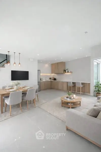 Spacious open-plan living room with modern kitchen and dining area, featuring elegant decor and ample natural light.